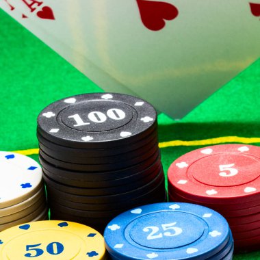 Kumar ve kumarhane gibi yeşil bir tuval üzerine düşen kupa as 'ın arka planına karşı parlak poker fişleri
