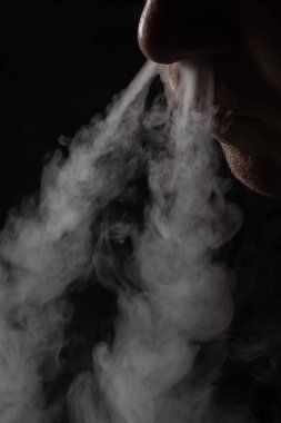 Sigara içen kişi, kötü alışkanlık ve elektronik sigara kavramının arka planında burnundan iki adet gri buhar salıyor.