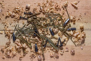 Bir tornavida için çivi, vida ve çeşitli başlıklar çok renkli bağlama araçları ahşap bir işyeri üzerinde uzanır endüstri ve ahşap işçiliği kavramı