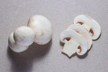 Dilimlenmiş ve tüm şampiyon mantarları gri plastik bir tahta üzerinde yakın plan yemek ve pişirme konseptiyle