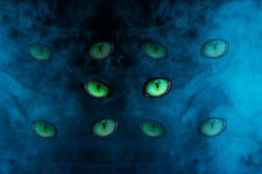 Mavi sigarada parlayan beş çift yeşil kedi gözü gizemli bir soyutlama.