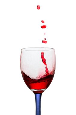 Bardaktan fırlayan parlak kırmızı şarap damlaları beyaz arka plandaki üzümlerden gelen popüler alkollü içecek kavramına dayanır.