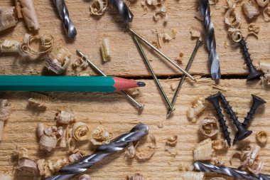 Endüstriyel soyutlama. Basit kalem çivileri. Vidaları ve metal matkapları ahşap bir masa üzerinde.