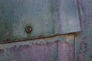 Metal yapının yüzeyi ki bu levhalar birbirine vidalanır ve kısmen eski bir boya arka planıyla kaplanır.