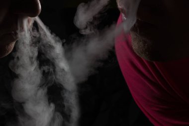 İki nefes ver, siyah arka planda gri sigara buharı burun sigara ve bağımlılık kavramı.