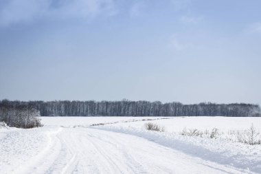 Mavi gökyüzünün altında beyaz karlı yol aydınlık kış günü