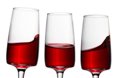 Kırmızı şaraplı üç şeffaf bardak ve beyaz arka planda farklı sıçramalar. Alkol tasarımı için nesneler.