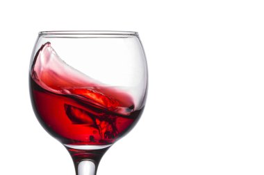 Bardakta küçük bir kırmızı şarap dalgası. Beyaz bir arka planda lezzetli bir alkollü içecek serpintisi.