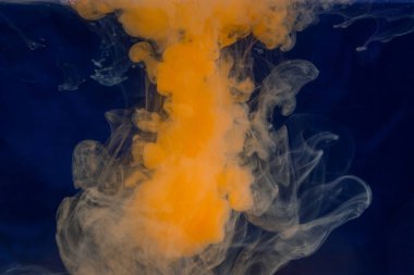 parlak turuncu boya suda çözünür koyu mavi arka planda güzel bir soyutlama