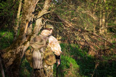 Metal dedektörü ve gizemli bir ormanda büyük bir sırt çantası olan turist. Aktif dinlenme ve doğa yürüyüşü kavramı.