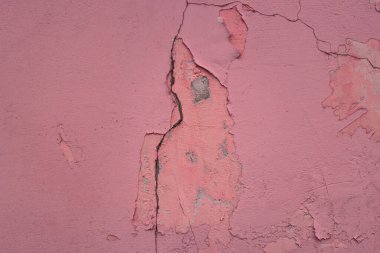 Çatlak boya çatlakları ve gri beton döşemeleri olan eski bir binanın parlak pembe duvarı.
