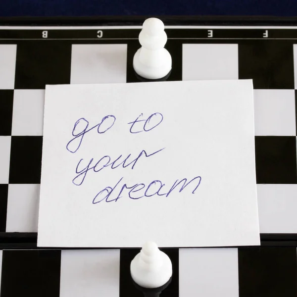 inscription in English go to your dream on a piece of paper on a chessboard pawn goes to the queen