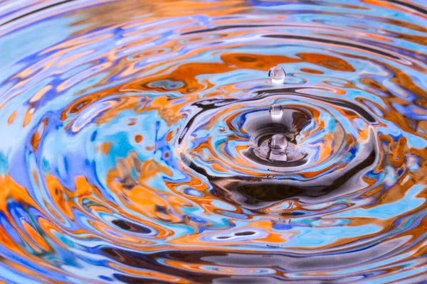 Düşen bir damladan küçük bir su patlaması parlak renkli soyutlama