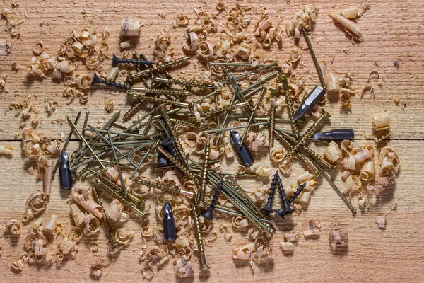 Bir tornavida için çivi, vida ve çeşitli başlıklar çok renkli bağlama araçları ahşap bir işyeri üzerinde uzanır endüstri ve ahşap işçiliği kavramı