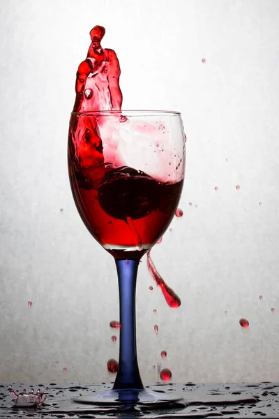 Hohe Spritzer Rotwein Einem Glas Vor Grauem Hintergrund Helle Farbspritzer — Stockfoto