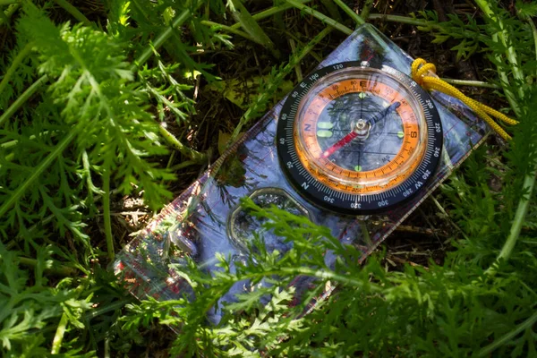 compass is in the green grass An arrow points to the north an accessory for orienteering and an assistant in hikes.