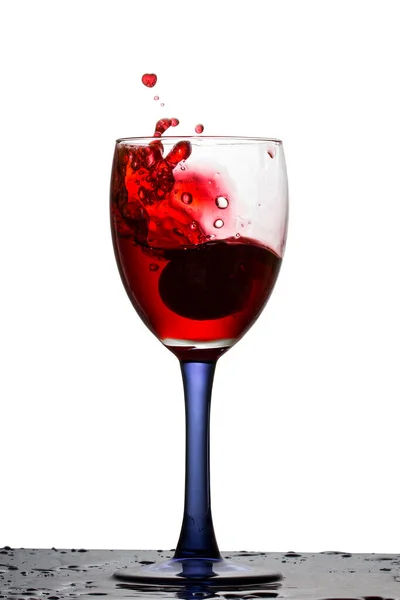 Vino Rosso Brillante Spruzzando Bicchiere Con Uve Cadute Uno Sfondo — Foto Stock