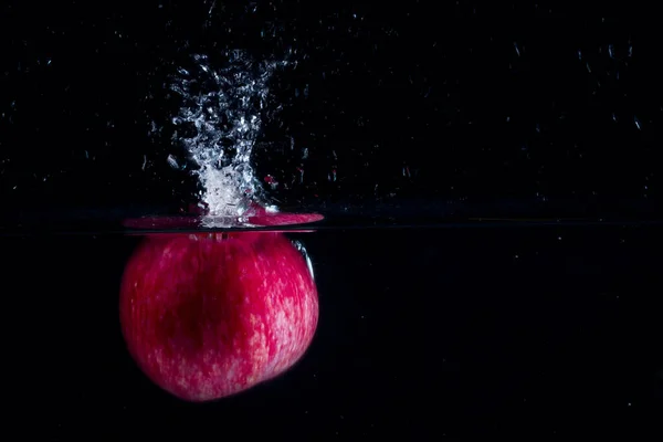 어두운 배경에 속으로 떨어진 사과는 먹는다는 개념의 표면에 아름다운 물줄기를 — 스톡 사진