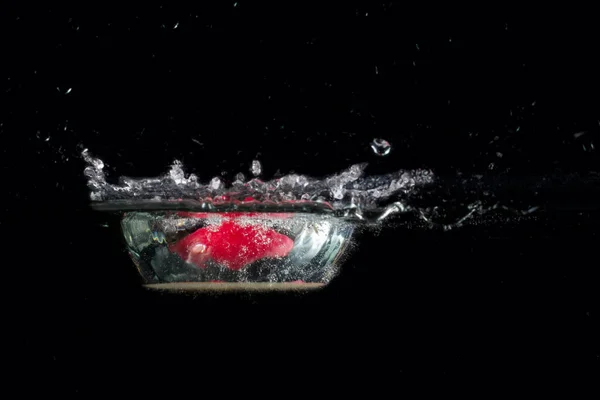 Jasny Plusk Wody Wewnątrz Którego Znajduje Się Kawałek Jabłka Czerwoną — Zdjęcie stockowe