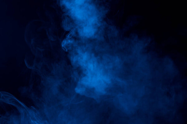 Partially bright and dense cloud of blue steam on a dark background mystical abstraction background for design