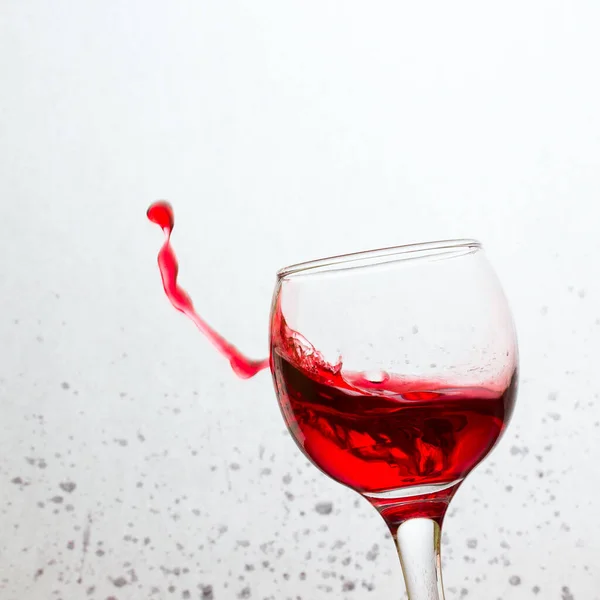 Ένα Κεκλιμένο Ποτήρι Που Πιτσιλάει Κόκκινο Κρασί Φωτεινό Γκρίζο Φόντο — Φωτογραφία Αρχείου