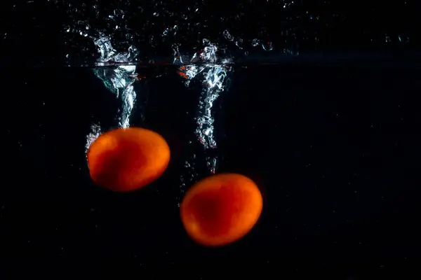 Two Red Tomatoes Fall Bottom Leaving Beautiful Splashes Water Dark — Stock Photo, Image