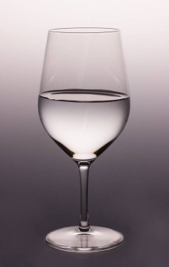 Gri arka planda su bulunan yüksek şeffaf cam çeşitli içecekler için güzel bir kap.