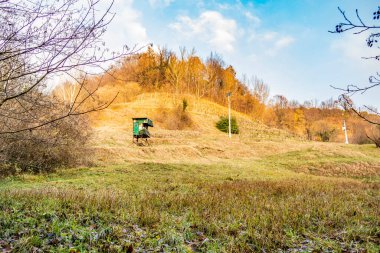 Sarı ceketli bir adam toprak bir yolda traktör sürüyor.