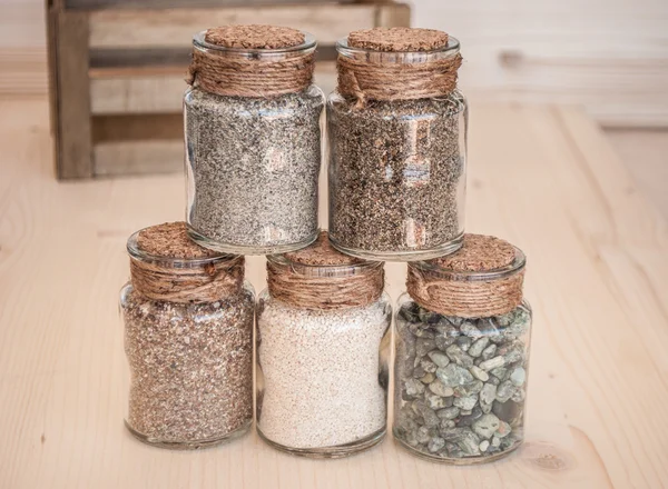 Petits bocaux en verre avec du sable et des pierres de la plage — Photo