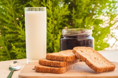 bir bardak süt ve meyve ile ekmek üzerine vişne reçeli ile kahvaltı