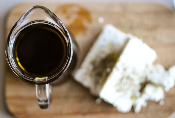 Close up of feta cheese(Greek cheese) slices on a wooden serving board and a bottle of olive oil in nature light — Stock Photo, Image