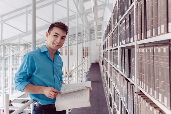 Genç adam öğrenci Kütüphanesi'nde kitap okuyarak öğrenme