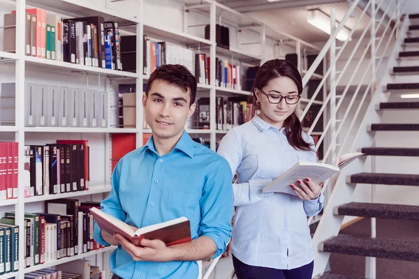 Étudiants lisant ensemble un livre dans la bibliothèque — Photo