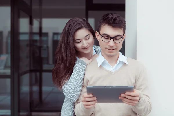 Twee aantrekkelijke studenten leren en op zoek in tablet pc op campus buiten — Stockfoto