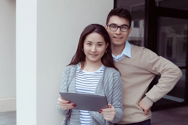 Twee aantrekkelijke studenten leren en op zoek in tablet pc op campus buiten — Stockfoto