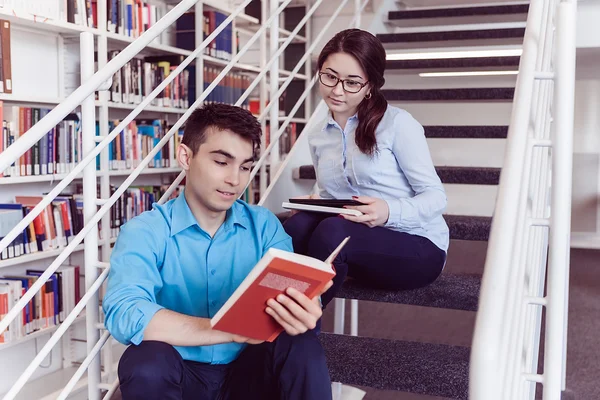 Uczniowie wspólnie czytania książki w bibliotece — Zdjęcie stockowe