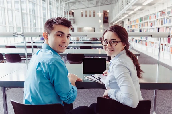 Jonge studenten die studeren met tablet pc in de bibliotheek — Stockfoto