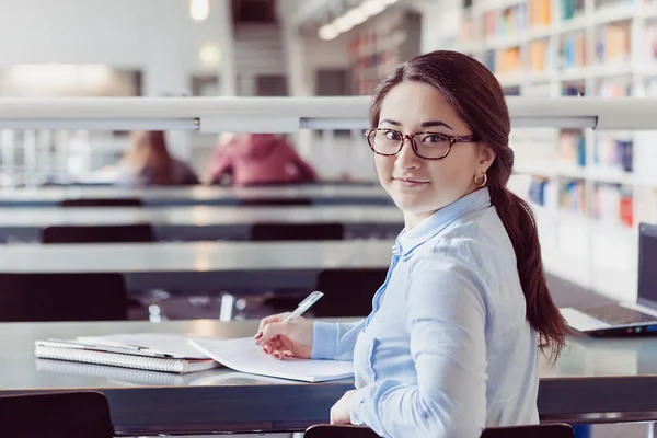 Jonge vrouw leren van leerlingen in de bibliotheek — Stockfoto