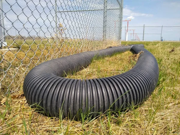 Großaufnahme Eines Gewellten Schwarzen Kunststoffrohres Auf Dem Rasen Zaun Und — Stockfoto