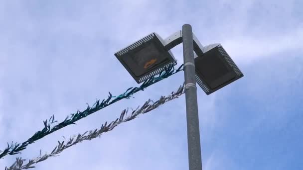 Slow Motion Glänsande Tinsel Knuten Till Stolpe Fladdrar Vinden Gatlykta — Stockvideo