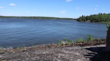 Batı Hawk gölü kıyısındaki kayalık yamaçtan yuvarlanan bir kaldırım taşının yakın çekimi. Arka planda gemiler yüzüyor..