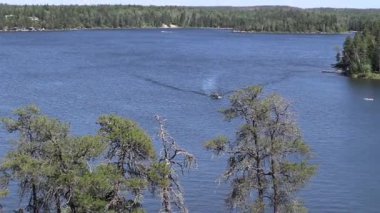 Tekne Batı Hawk Gölü 'nden geçiyor. Orman arka planda.