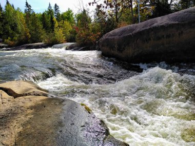 Pinawa Barajı: Nehir, taştan banka ve ormanın panoramik manzarası