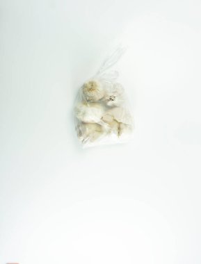 Beyaz arka planda şeffaf beyaz plastiğe sarılmış sarımsak..