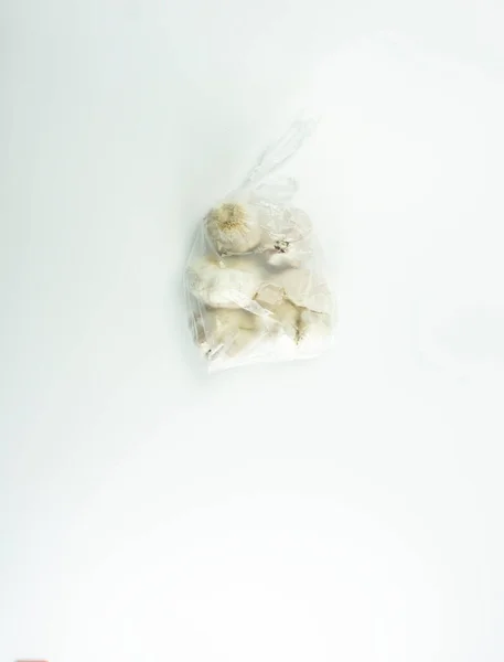 用透明的白色塑料包裹在白色底座上的大蒜 — 图库照片