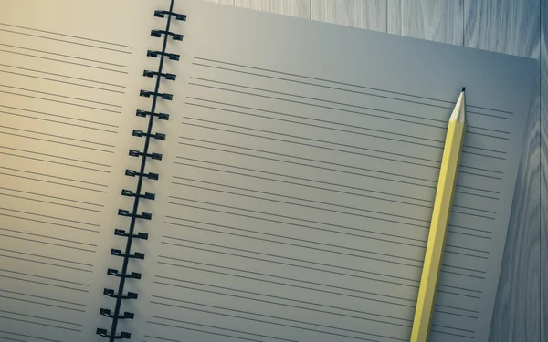 Lápis no caderno verificado sobre fundo de madeira — Fotografia de Stock