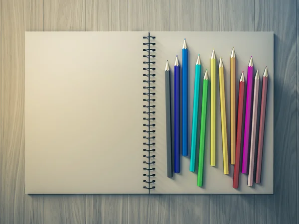 Lápis de cor no caderno verificado no fundo de madeira — Fotografia de Stock