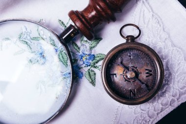 Beyaz mendilin üzerine eski model pusula büyüteç.