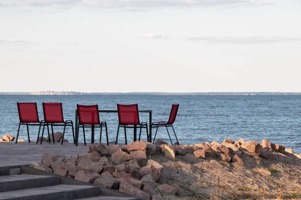 Nehir manzaralı, önünde renkli sandalyeler olan.