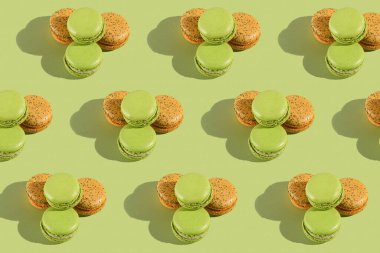 Bir kurabiyenin sert ışık deseni - iki yeşil ve bir turuncu - açık yeşil yüzeyde fotoğraflanmış.